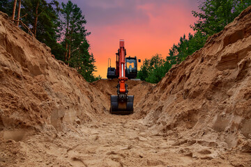 Excavator dig trench at forest area on amazing sunset background. Backgoe on earthwork for laying...