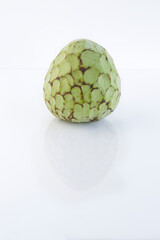 Custard apple reflected on a glass table against white background with copy space