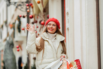 Beautiful young woman is doing Christmas shopping. Portrait of a young woman in a red beret on the street of a European city.