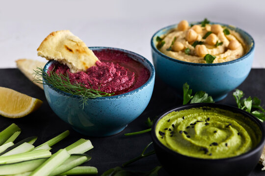 Various types of hummus served with fresh vegetables and pita bread
