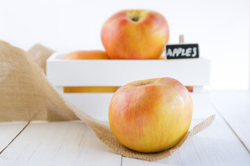 White wooden box full of fresh apples and a little chalkboard isolated on a white background