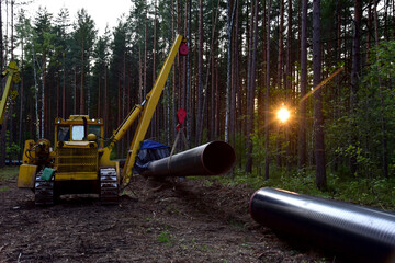 Construction natural gas pipeline project on sunset background. Crude oil Transmission in pipe to LNG plant (shipped by LPG tanker). Building of transit petrochemical pipe