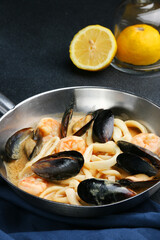 frying pan with seafood and lemon on background. shrimp squid and mussels fried in white wine