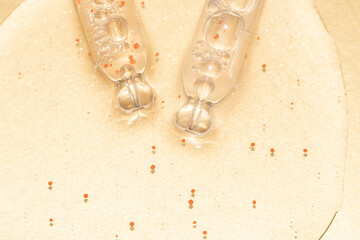 close up macro of two pipette droppers with liquid with particles on a gold background