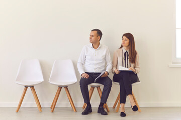 Obraz premium Confident young job candidates sitting on chairs in the hall waiting for their interview