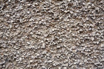 Gray Cement wall background textured with stone chips. Concrete wall of a building with stones of different sizes, close-up view.