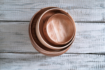Stack of wooden dishes of different diameters from elm on wooden background