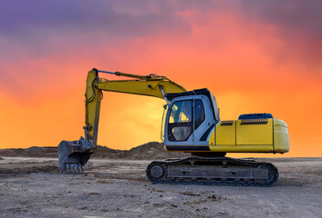 Excavator during earthmoving at construction site on sunset background. onstruction machinery for excavating. Tower cranes lifting a concrete bucket for pouring of concrete into formwork