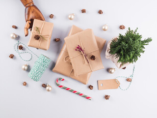 Christmas gifts wrapped in craft paper, pine cones and minimal festive ornament in wooden hand. Flat lay