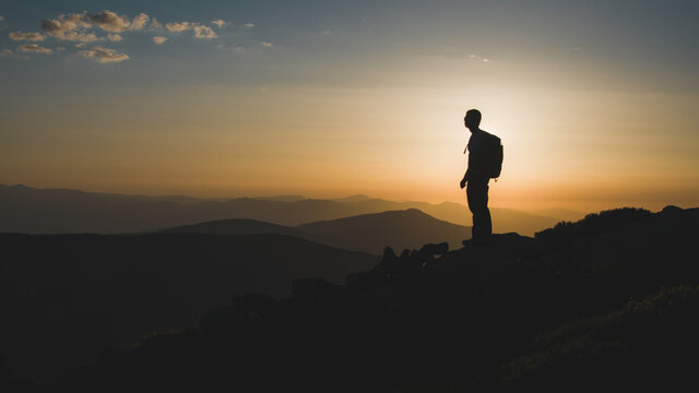 Silueta de senderista a contraluz viendo el amanecer en la Sierra de Guadarrama en Madrid