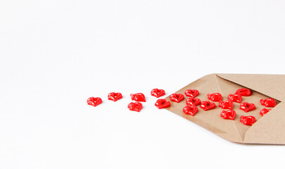 An envelope made of Kraft paper on a light background from which red kisses spilled out.