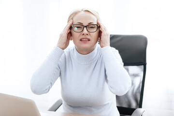 Woman sitting in chair with severe pain in head. 