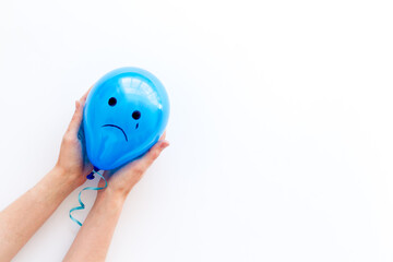 Sadness emotion face on balloon - depression mood background. Top view, copy space