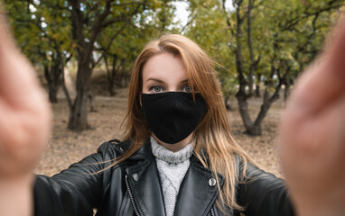 Woman with reusable face mask taking selfie outdoors at the park.