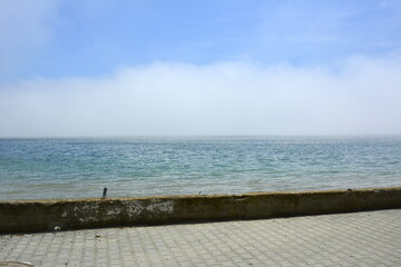 Fototapeta premium Ravda, Bulgaria. May, 20, 2014. Seashore with white cloud covering water. Promenade edge with no people