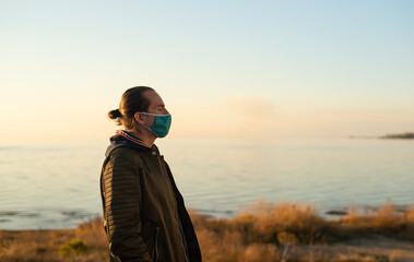 Fototapeta premium Man with hair bun and reusable face mask outdoors.