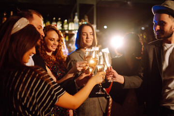 Happy friends clinking glasses of champagne at party  in a nightclub. Young people celebrating...
