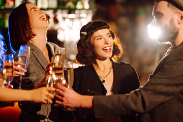 Happy friends clinking glasses of champagne at party  in a nightclub. Young people celebrating winter holiday together with champagne.  Party, celebration, drink, birthday concept.