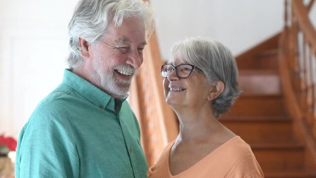 portrait and close up of two happy seniors or mature and old people smiling and looking at the camera - couple of pensioners having fun at home
