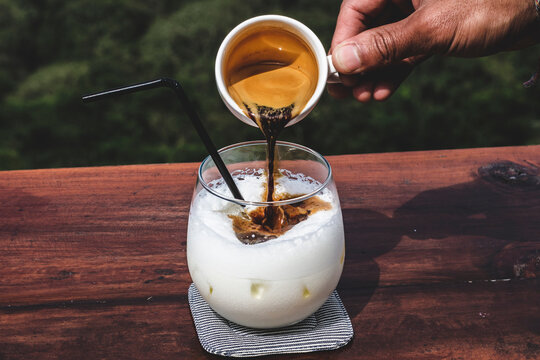 Pouring espresso into an iced latte
