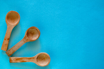 Three small wooden spoons next to each other on a blue surface.