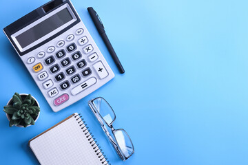 Calculator keypad on a blue background.Notebook, pen, glasses, desktop. Finances Top view. Copy space