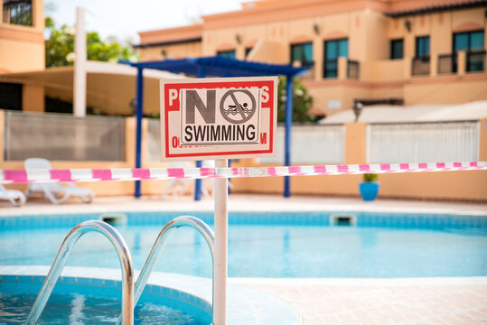 No swimming sign. Pool under closure. Consequences of self isolation during coronavirus times. Restrictions for any group activities. Abandoned swimming pool at the time of epidemic. Health measures.