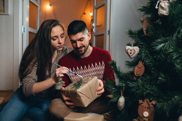 couple decorating christmas tree and preparing gifts for new year