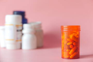 close up of pills and capsule container on pink background 