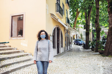 Young woman in a blue mask walking on a city street