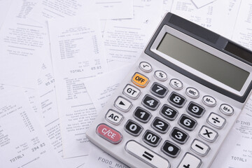 Calculator for counting on a pile of checks from purchases from the store on a wooden background. Top view. Place for text.Copy space