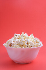 Popcorn in bowl on a red background. Close up. Top view