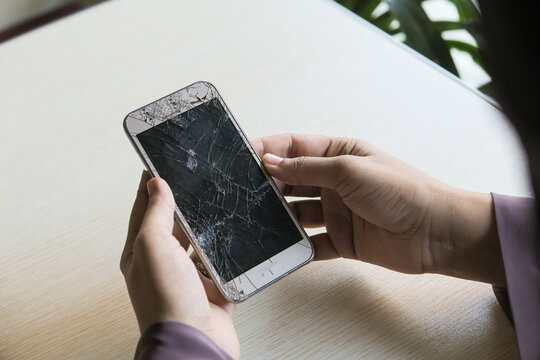 Close up of man hand holding broken smart phone.