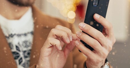 Caucasian young male hands holding gadget and typing on smartphone on Xmas Eve on street. Man fingers tapping on mobile phone sending xmas congratulation. Winter festive period. Close up concept