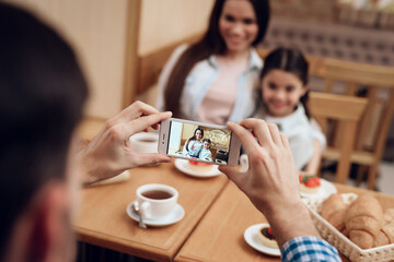 Young Father Taking Photo of Family in Cafeteria.