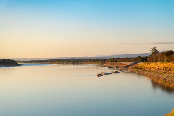 Golden hour sunset light over Mekong riverbank landscape against sunset sky reflection on calm water.
Bueng Kan, Thailand.