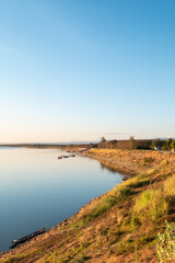 Obraz premium Golden hour sunset light over Mekong riverbank landscape against sunset sky reflection on calm water. Bueng Kan, Thailand.