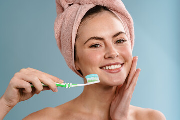 Shirtless happy girl in towel holding toothbrush with toothpaste