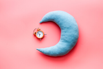 Flat lay of sleeping pillow with alarm clock, top view