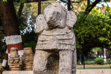 An old broken elephant trunk statue made of rock amongst of tree in kolhapur city , Maharashtra.