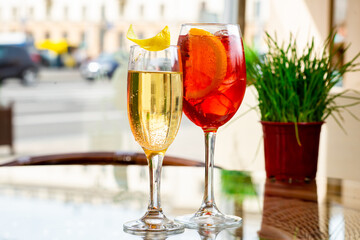 Two glasses of sparkling wine cocktails and Aperol Spritz cocktails on table in terrace of restaurant or summer cafe