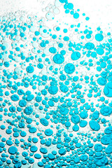 Abstract dynamic flow of blue drops in water, falling, with selective focus, on illuminated white background, in vertical