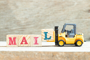 Toy forklift hold letter block l to complete word mail on wood background