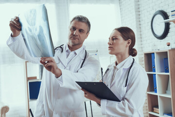 Male doctor showing woman x-ray in office. 