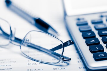 Pen, Eyeglasses and Calculator on Financial Figures