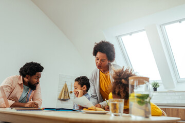 Afro students doing homework at home with school books helped by their parents. Mom and dad...
