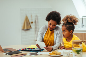 Naklejka premium Mother helping her daughter with her homework at home