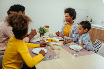 Fototapeta na wymiar Cute afro family having lunch together at home