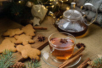 Christmas composition with a cup of tea, teapot and gingerbread cookies in a festive decor.