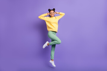 Fototapeta na wymiar Full size profile photo of optimistic girl jump show v-sign wear yellow shirt trousers sneakers isolated on lilac color background